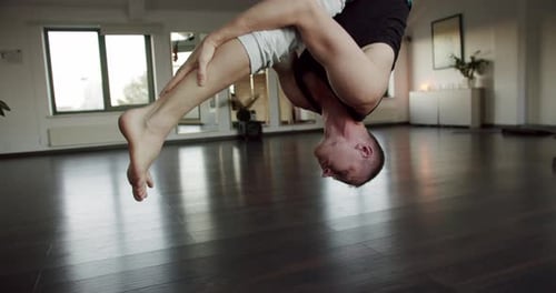 Man Doing Fly Yoga Exercise and Hanging Inverted Using Fabric Hammock at Studio