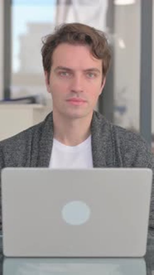 Man Smiles While Working at Laptop