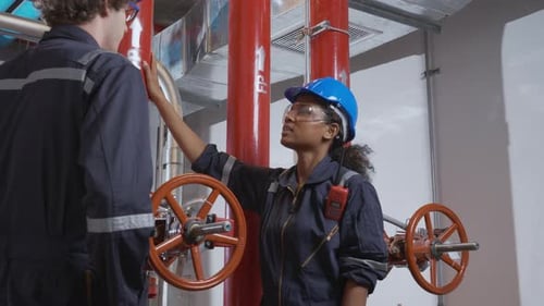 Young woman and man engineer check and examining pipeline and discussion in the factory.
