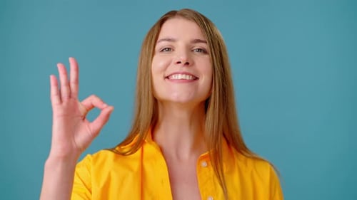 Smiling Woman with OK Hand Gesture on Blue