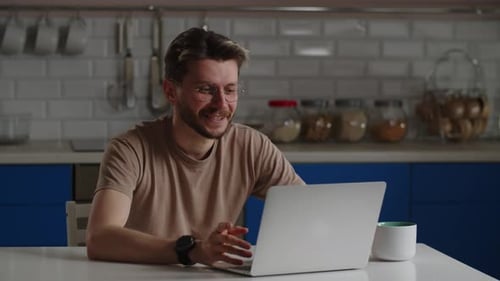 Man Enjoying Video Call on Laptop in Kitchen