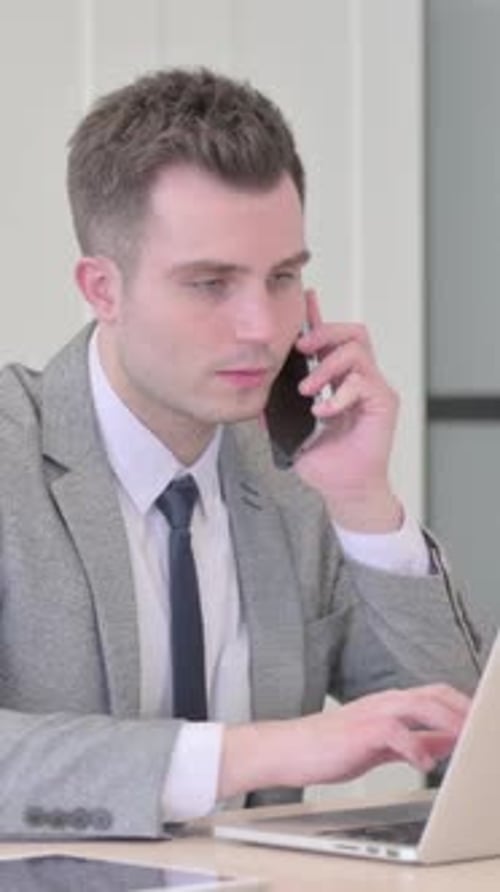 Young Adult Man Talking on the Phone at Desk