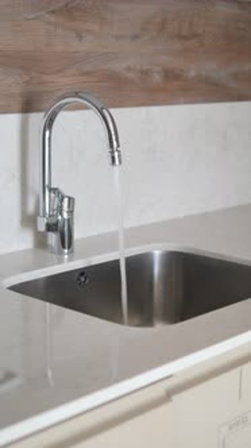 Running Faucet in Clean, Modern Kitchen Sink