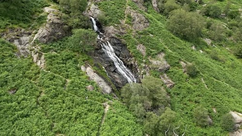 Waterfall Flowing Down Green Rocky Mountainside