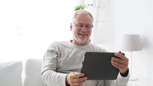 Senior Man Chatting on Tablet Video Call at Home