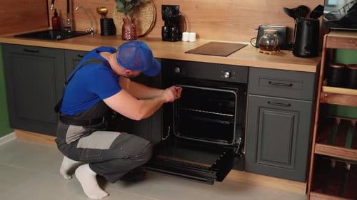 Man Repairs Oven Appliance in Kitchen Interior