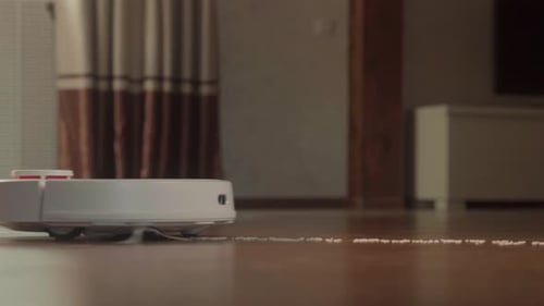 Weißer Roboter-Staubsauger reinigt den Boden im Schlafzimmer