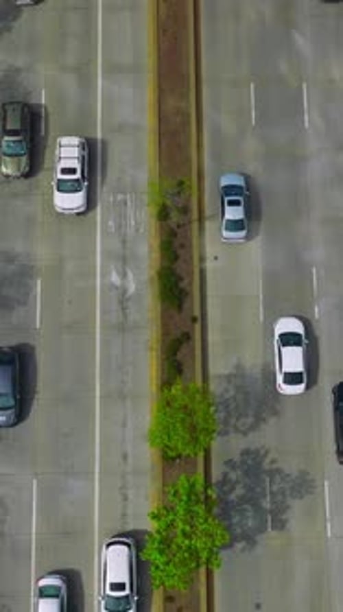 Wide road with several lanes with numerous cars driving on it.