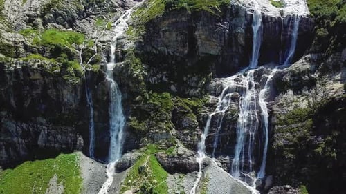 Majestätischer Wasserfall, der den moosigen Berghang hinunterstürzt
