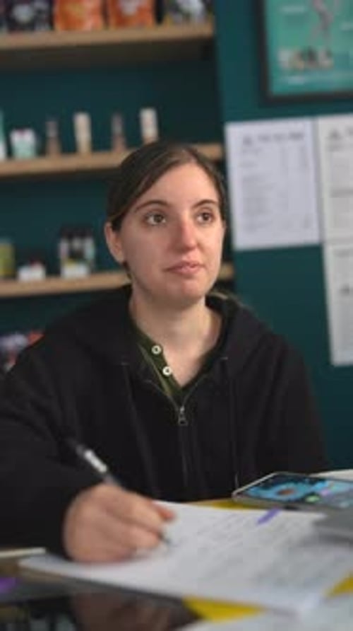 A Young Woman is Writing Notes in a Cozy Cafe Environment Focusing on Her Study and Education