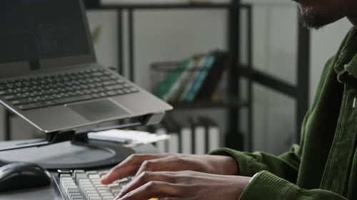 Schwarzer männlicher Programmierer Vibe Coding während der Arbeit an einer mobilen App im Büro