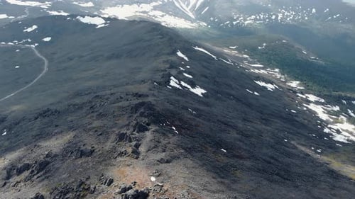 Scenic Route Through Rugged Mountain Terrain Vast Horizon Overlooking Rocky Slopes And Snow Patches