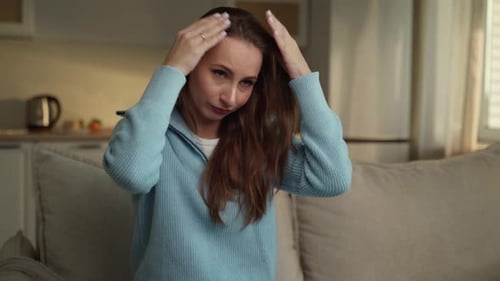 Woman Sitting on Couch Touching Her Hair