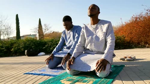 Men Kneeling in Prayer Outdoors in Urban Park