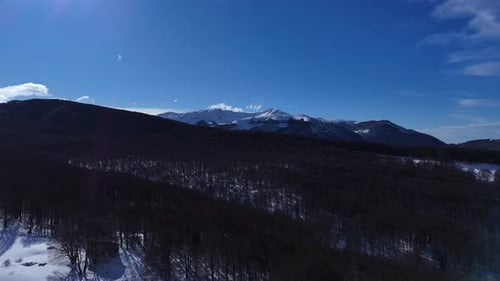 Drone Aerial Video Footage Flying Forward Over Snowy Forest Towards Mountain Peaks in Abruzzo Italy