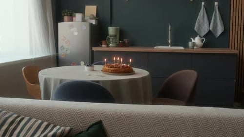 Birthday Cake with Burning Candles in Cozy Kitchen Interior