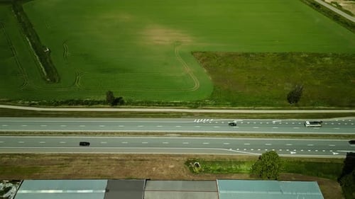 Aerial View of Cars on Country Highway Passing Through Farmland with Green Fields and Rural