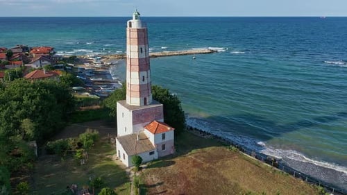 An old lighthouse near the sea with waves hitting the shore