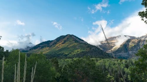 El amanecer ilumina una montaña en otoño mientras las nubes se arremolinan alrededor del pico: Time Lapse de gran angular