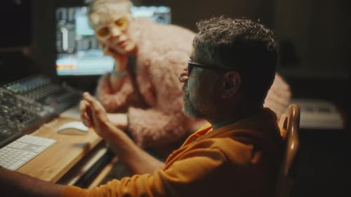 Female Singer Discussing Music with Sound Engineer in Recording Studio