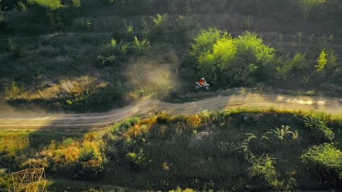 Aerial drone view of motorcyclists jumping from springboards at a motocross race, mud track, rally m