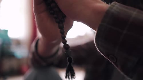 Nahaufnahme des Händehaltens und der Verwendung von Gebetsperlen für Gottesdienst und stille Meditation