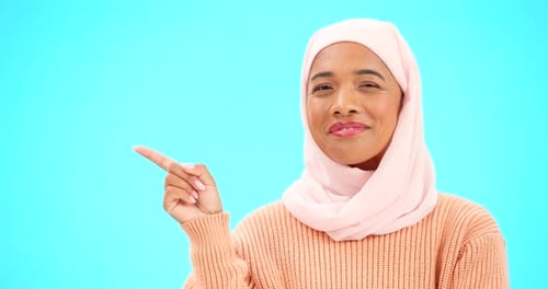 Woman in Headscarf Smiles and Points to Left