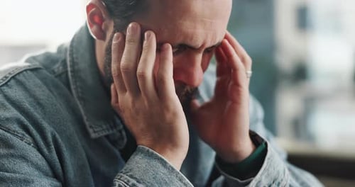 Worried Man Massaging Temples in Office
