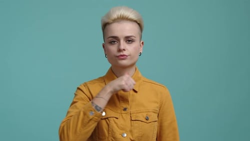 Woman Giving Thumbs Down on Turquoise Background