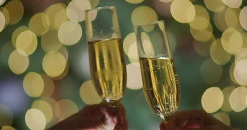 Deux mains avec des verres de vin mousseux clignotent sur fond de lumières floues