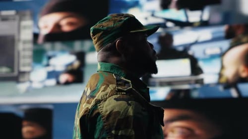 Man in Camouflage Watches Monitors in Control Room