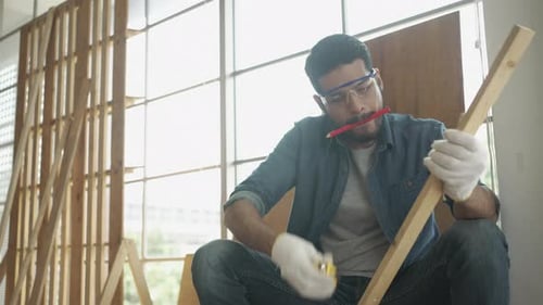 Man Measuring Wood in Workshop with Safety Glasses