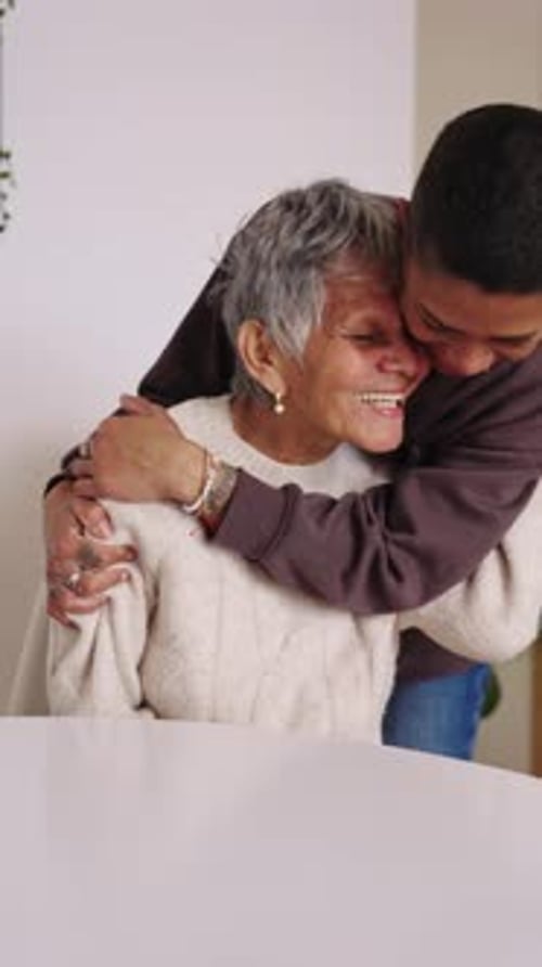Affectionate Young Woman Hugging Smiling Senior Woman Indoors