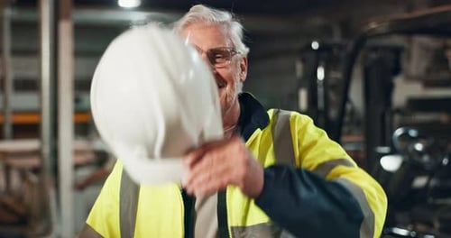 Senior Factory Worker Smiling and Holding Hard Hat