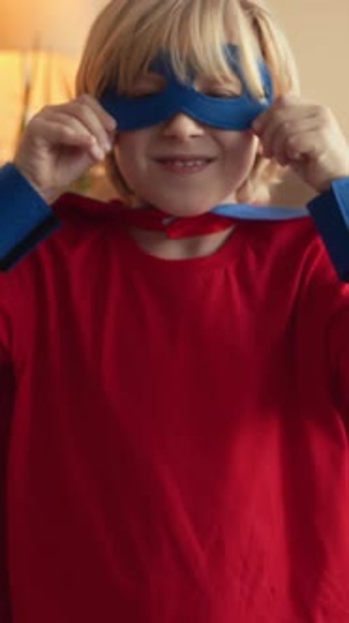 Enthusiastic Boy Puts On Superhero Mask and Cape