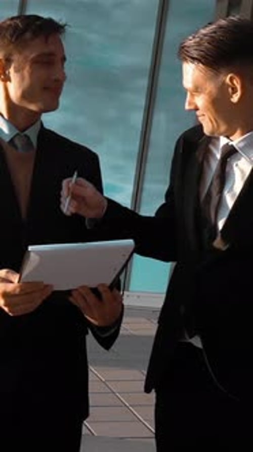 Men Discussing Tablet Outside Office Building