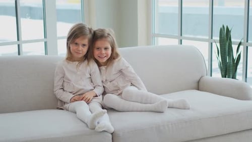 Two Young Girls Sitting Together on Couch Indoors