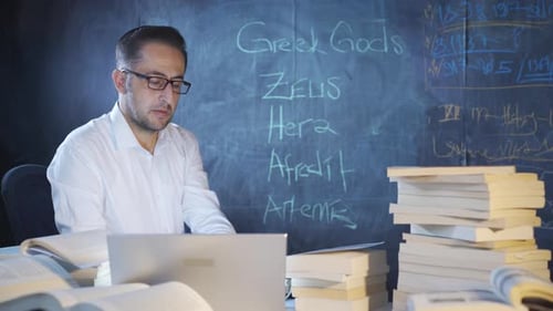 Historian man writing Greek Gods on blackboard.