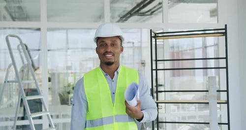 Portrait of african man specialist of building company which holding in hands draft with building