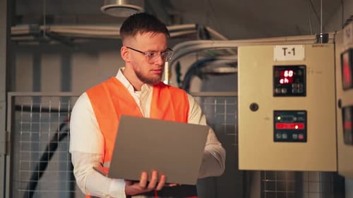 Engineer Monitors Industrial Systems Displaying Concentration and Concern