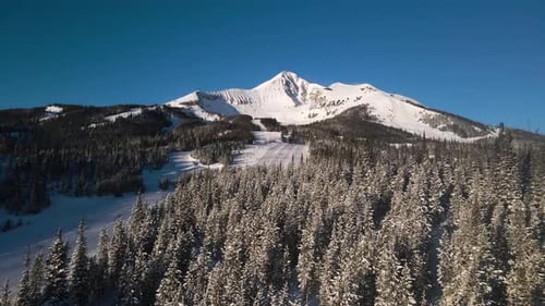 A drone shot of snowy Big Sky, Montana in winter, showcasing the ski resort and majestic mountain te