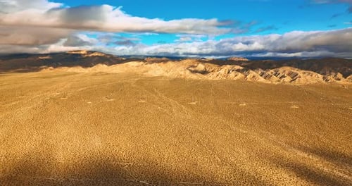 Plain deserted landscape surrounded by rocks. Beautiful blue sky with white clouds