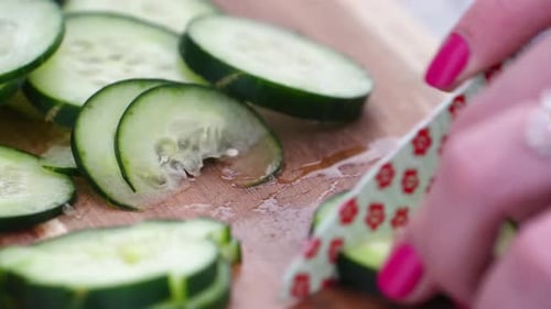 Woman Chopping Cucumber Slices into Cubes and Chunks, Close Up on Wooden Cutting Board with Small Kn