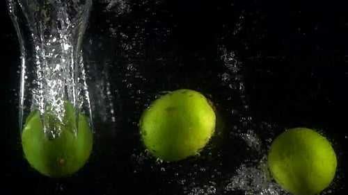 Limes Plunging into Water on Black Background