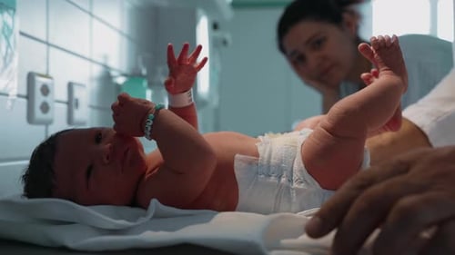 Newborn being examined by a doctor, close-up of doctor's hand, hospital setting, showing early