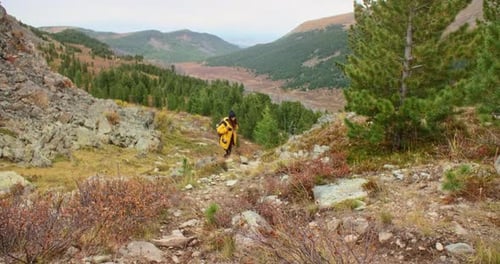 Hiker Walking Down Mountain Trail Exploring Wilderness in Autumn