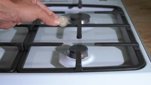 Coin Held Over Lit Gas Stove Burner Close Up