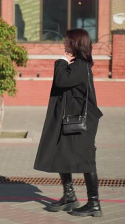 Sangle de sac à main ajustable pour dame passant devant un bâtiment en brique rouge