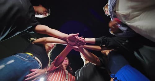 Diverse group joining hands in powerful gesture of solidarity, preparing to lift arms together