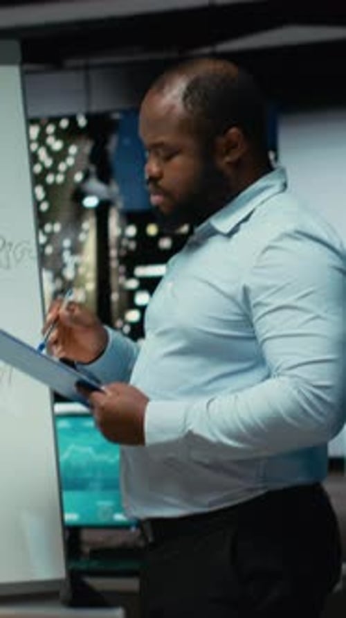 Man Reviews Charts in Dark Monitoring Office